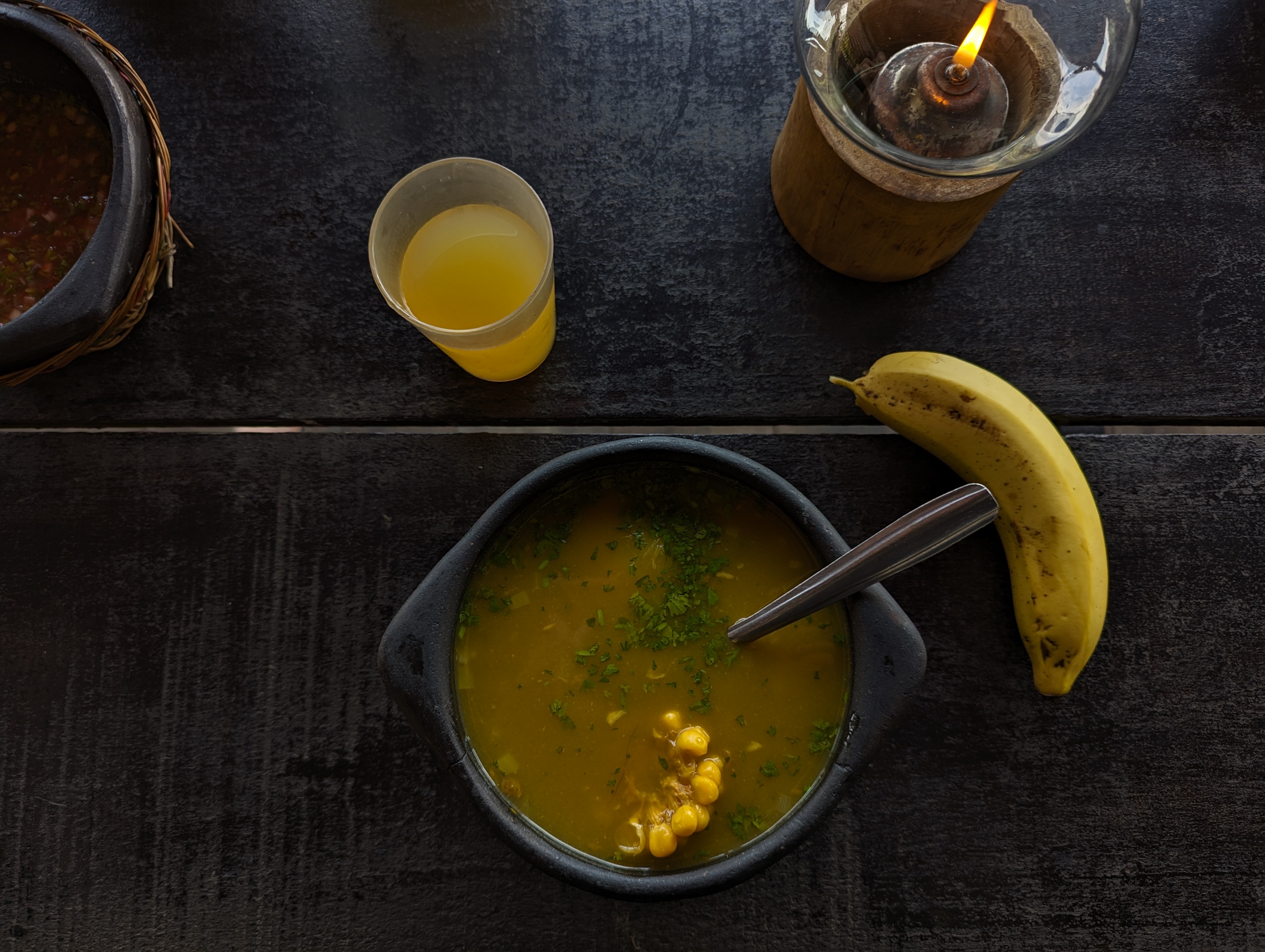 A black bowl full of delicious Sancocho with a banana as a side dish.